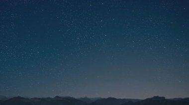 Gece gökyüzünde dağların manzaralı bir yıldız hareketi..