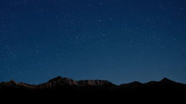 Gece gökyüzünde dağların manzaralı bir yıldız hareketi..
