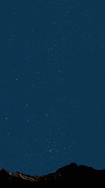 Gece gökyüzünde dağların manzaralı bir yıldız hareketi..