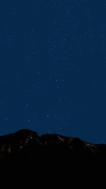 Gece gökyüzünde dağların manzaralı bir yıldız hareketi..