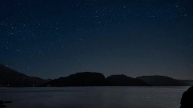 Gece gökyüzünde dağların manzaralı bir yıldız hareketi..