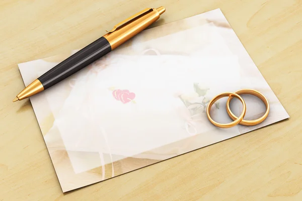 Anillos de boda, bolígrafo y tarjeta vacía en mesa de madera — Foto de Stock