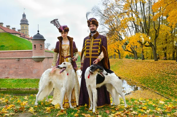 Casal em trajes medievais com cães borzoi — Fotografia de Stock