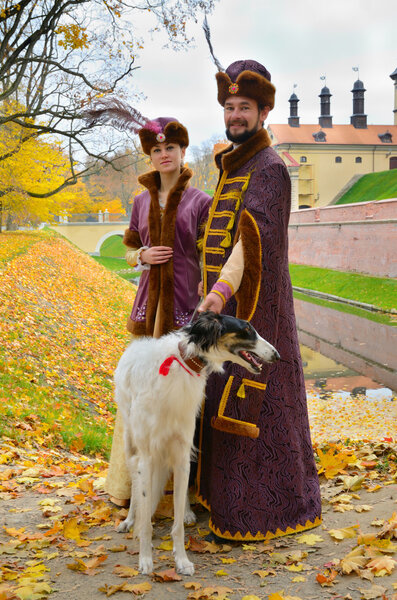 Couple in traditional medieval costumes with two borzoi dogs