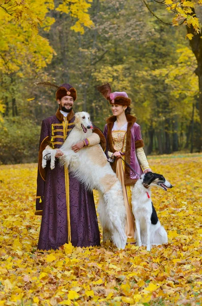 Coppia in costume medievale con due cani borzoi — Foto Stock