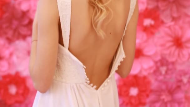 Hermosa novia ropa su vestido de novia en el fondo de las flores — Vídeos de Stock