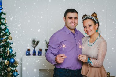 Mutlu çift ile birlikte yılbaşı ağacının yanında gülümseyen parıldıyor