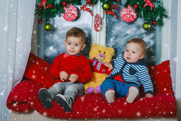 Dos hermanos sentados en la ventana decorada año nuevo — Foto de Stock