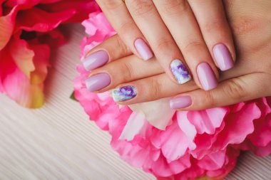 Lilac nail art with printed flowers on light background