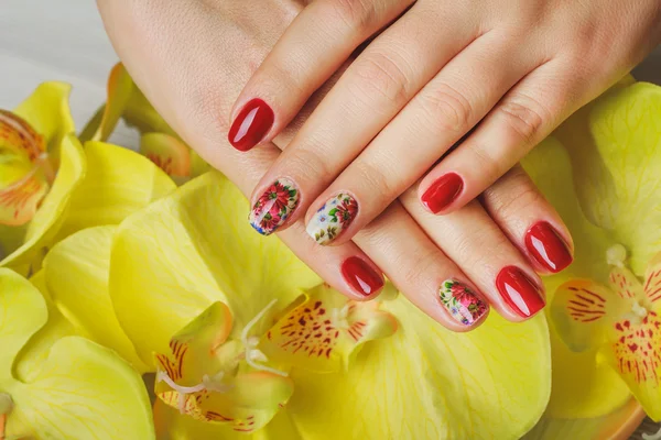 Red nail art with printed flowers — Stock Photo, Image