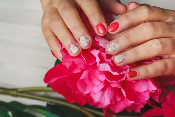 Red nail art with printed flowers on wooden background — 스톡 사진
