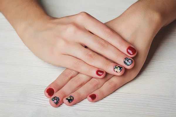 Red nail art with printed flowers on wooden background — Stockfoto