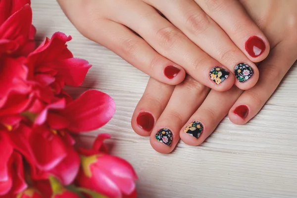 Red nail art with printed flowers on wooden background — 스톡 사진