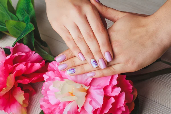 Lilac nail art with printed flowers on light background Stock Photo