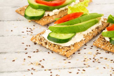 Kraker, peynir, avokado, salatalık, domates ve marullu sandviç..