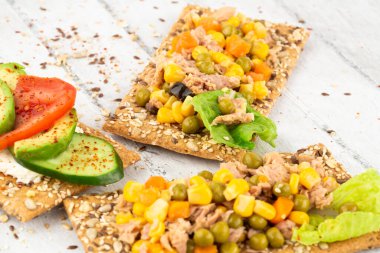 Krakerli sandviç, ton balığı, mısır ve havuç, gri ahşap arka planda..