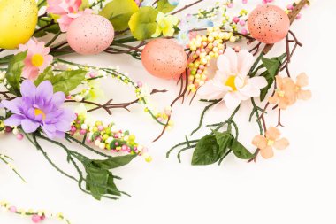 Beyaz arka planda Paskalya yumurtaları ve çiçekler.