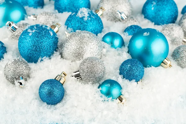 圣诞装饰用蓝色和灰色的球在人造雪的背景上 — 图库照片