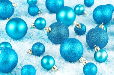 Yapay kar arka planında mavi toplarla Noel süslemesi.