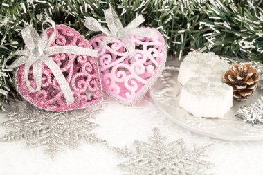 Parlak arka planda çelenklerle, kalplerle, mumlarla ve kar taneleriyle Noel süslemesi.