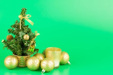 Noel süslemesi köknar ağacı, altın toplar ve yeşil arka planda cam mum..
