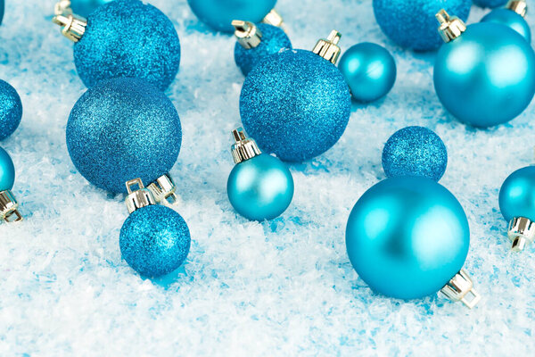 Christmas decoration with blue balls on the artificial snow background.