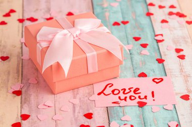 Yay ile hediye kutusu, metin ile kağıt kart Seni seviyorum, küçük kırmızı ve pembe kalpler renkli ahşap arka plan.