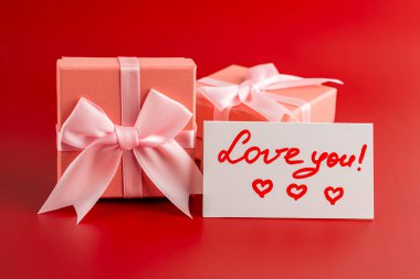 İki pembe hediye kutusu, üzerinde kırmızı arka planda 