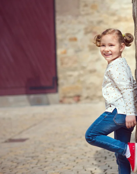 Pretty little girl standing near the wall — Stock Photo, Image