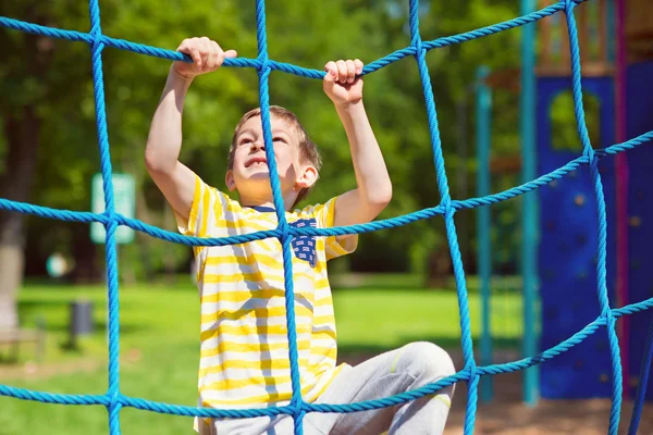 Menino feliz brincando no playground no verão — Fotografia de Stock