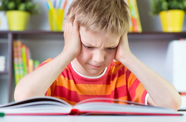 Elementary school boy at desk reading boock — Stock Photo, Image