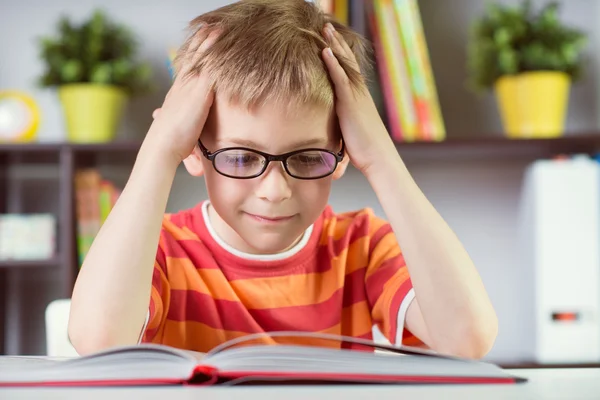 Хлопчик початкової школи за столом читає бут — стокове фото