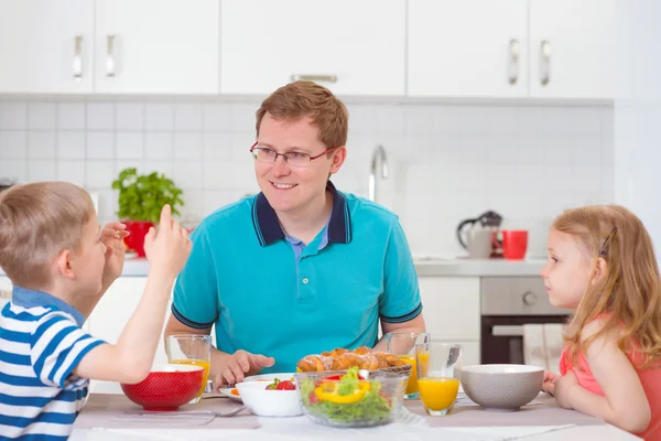 Smiling family eating breakfast in kitchen — Stock Photo, Image