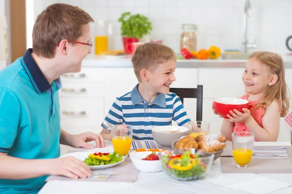 Smiling family eating breakfast in kitchen — Stock Photo, Image