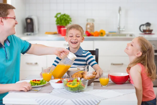 Улыбающаяся семья завтракает на кухне — стоковое фото