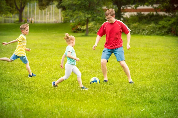 Gelukkige familie speelt voetbal in zonnig park — Stockfoto