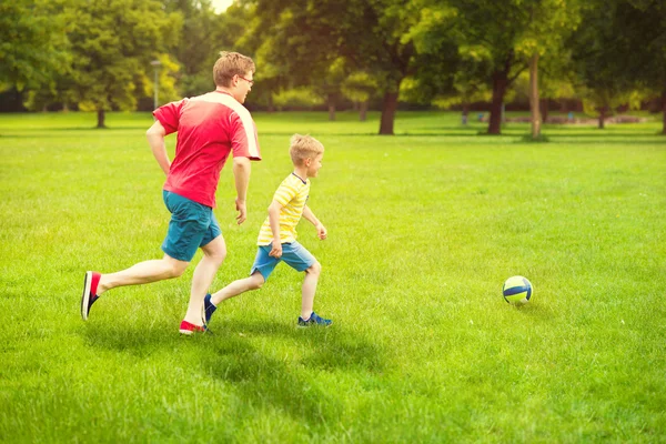 Famiglia felice gioca a calcio nel parco soleggiato — Foto Stock