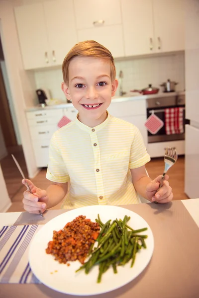 Joven niño feliz diligente en una mesa comiendo comida saludable con Cu —  Fotos de Stock