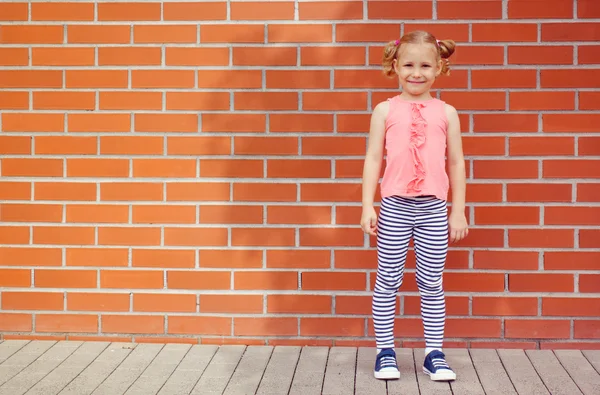Tuğla duvar arka plan gülüyor küçük çocuk kız portresi — Stok fotoğraf