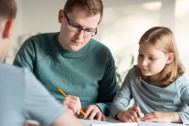 Genç baba covid-19 tecridi sırasında çocuklarına evde eğitim konusunda yardım ediyor.