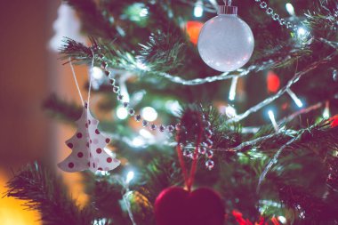 Toplarla süslenmiş Noel ağacının yakın fotoğrafını çek. Karanlıkta kırmızı kalpler, ama yılbaşı arifesinde yılbaşı ışıkları.