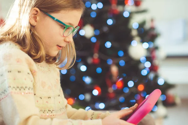 Cute Little Girl Dziecko Gra Tabletem Siedzi Pobliżu Urządzone Choinki — Zdjęcie stockowe