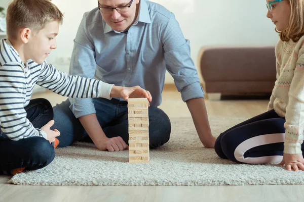 年轻快乐的父亲和他的两个可爱的孩子在家里玩木块 — 图库照片