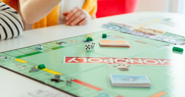 KIEL, GERMANY - 14 Şubat 2021: Mutlu çocuklar aileleriyle sıcak bir aile akşamında masa oyunu oynarken eğleniyorlar