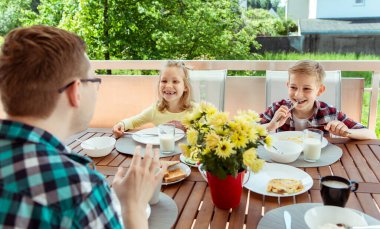 Genç ve mutlu bir aile kahvaltıda büyük teraslarda eğleniyor.