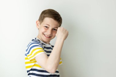 Beyaz duvar arkasında duygusal hareketlerle poz veren mutlu ve yakışıklı bir gencin portresi.