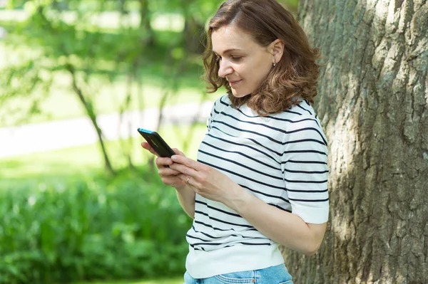 Giovane Bella Donna Con Suo Cellulare Sotto Albero Nel Parco — Foto Stock