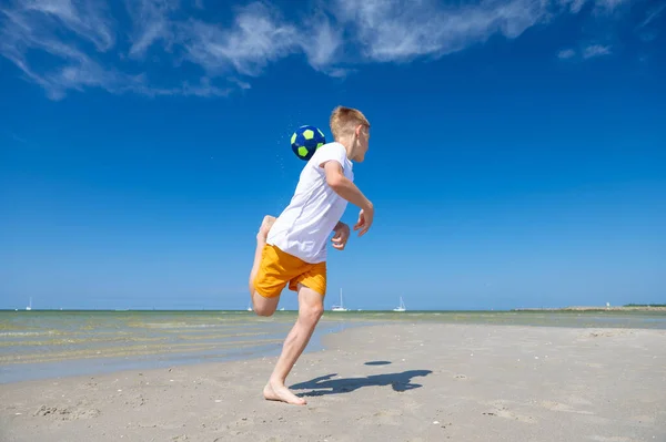 幸せなティーン男の子遊びますとともにボールオンビーチで夏晴れ日とともに青空上の背景 — ストック写真
