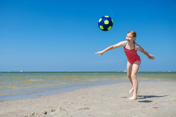 可爱的小女孩在阳光明媚的夏日在海滩上玩球 玩得很开心 — 图库照片