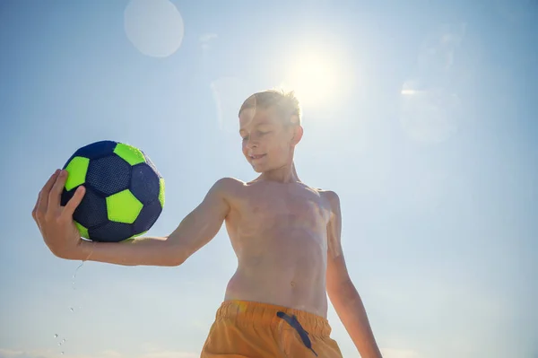 夏の晴れた日に太陽の光を背景にビーチでボールとバレーボールをプレイ10代の男の子の肖像画 — ストック写真
